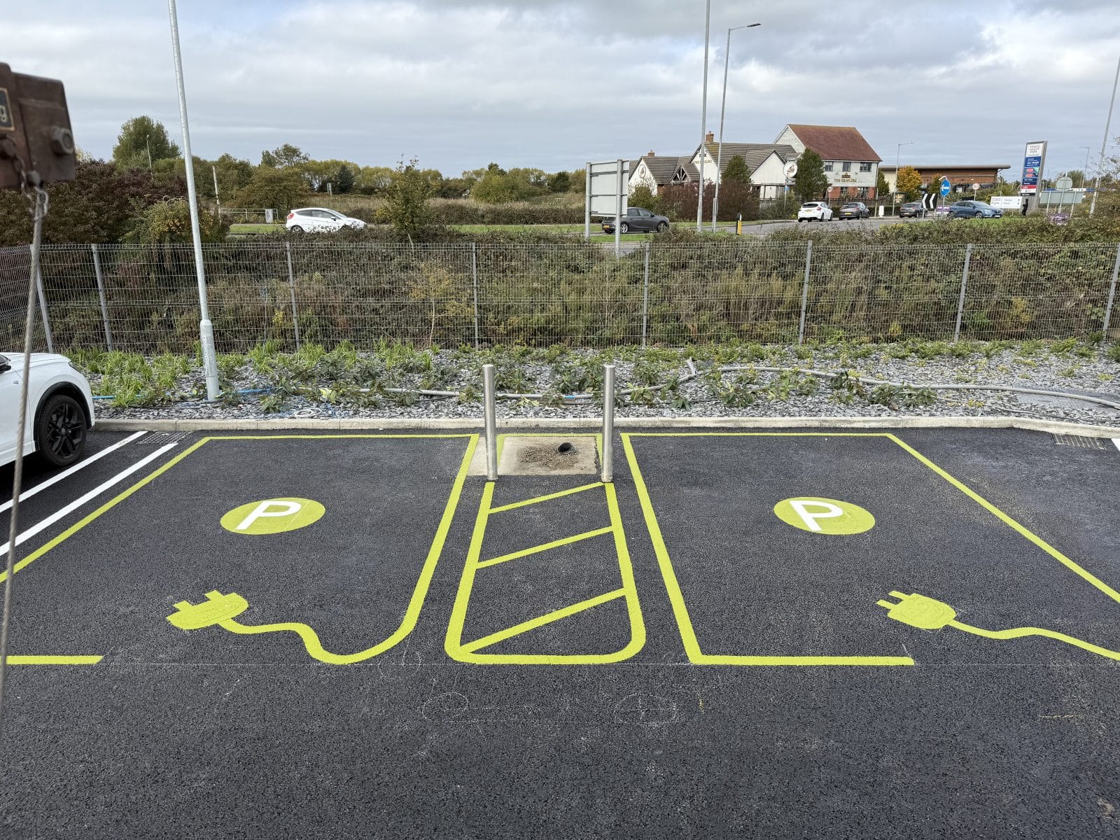 Parking lot with yellow line markings for vehicle spaces near a residential area.